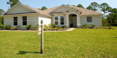 A house is for sale and has a sign posted in the front yard.