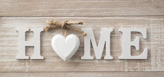 A rustic image of the word "HOME" spelled out in white block letters over a wood background.